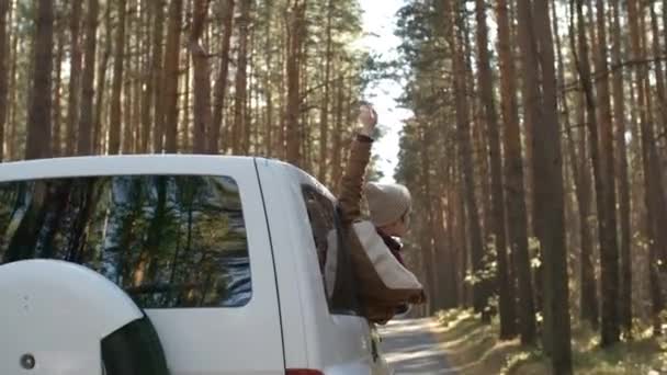 森林旅行中に車の窓の外で自然を楽しむビーニーで若い白人女性の中出し — ストック動画
