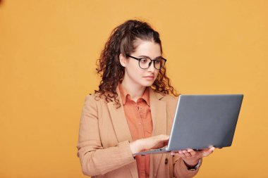 Seminer için sunum hazırlarken dizüstü bilgisayara bakan gözlüklü ciddi genç öğretmen veya öğrenci