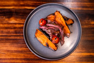 Domatesli güzel et tabağı ve tatlı patates, yemek sunumu.