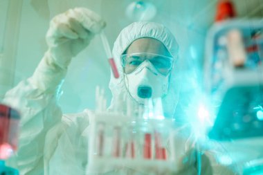 Koruyucu giysi ve maske üzerinde çalışan bir laboratuvar uzmanı.