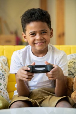 Afrika kökenli neşeli, küçük bir çocuk. Joystickli. Gülümseyerek sana bakıyor.