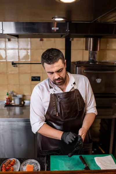 Chef Barbudo Ocupado Delantal Cuero Pie Mostrador Poner Guantes Las —  Fotos de Stock