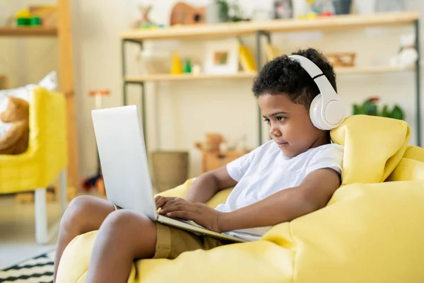 Geconcentreerde Schattige Schoolkind Hoofdtelefoon Kijken Naar Laptop Display Tijdens Het — Stockfoto