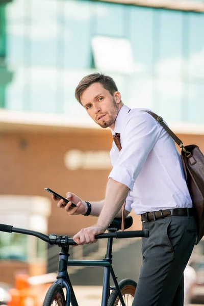 Bisikletli Akıllı Telefonlu Genç Adam Modern Merkezinin Arka Planında Kameranın — Stok fotoğraf