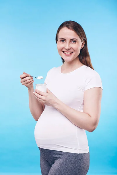 Hübsche Schwangere Aktivkleidung Hält Ein Kleines Plastikgefäß Mit Bio Joghurt — Stockfoto