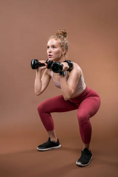 Young Strong Fit Sportswoman Tracksuit Sitting Squats Lifting Dumbbells While — Stock Photo, Image