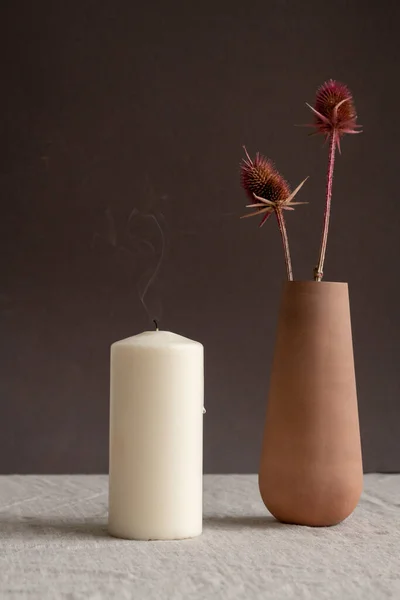 芳香のキャンドルと手作りの茶色の粘土の花瓶や黒壁に対してテーブルの上に立つ2つの乾燥した野の花とジャグを吹きます — ストック写真