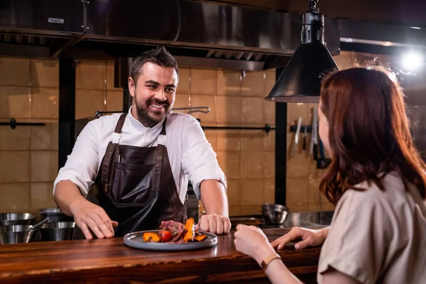 Chef Barbu Souriant Dans Tablier Debout Comptoir Bavarder Avec Femme — Photo