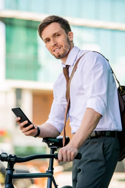 Joven Hombre Negocios Sonriente Sentarse Bicicleta Mientras Usa Teléfono Inteligente — Foto de Stock