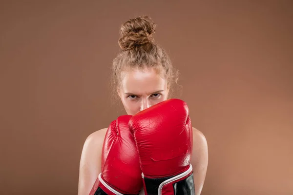 若いです積極的な女性選手とともにブロンド巻き毛保持手で赤ボクシング手袋で彼女の顔に近いですあなたを見ながら前に戦います — ストック写真