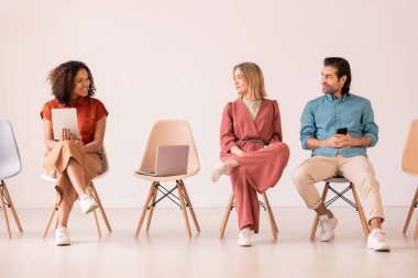 Akıllı telefonlu mutlu genç çift dokunmatik sayfalı karışık ırk kızına bakıyor ve online haberleri ya da paylaşımları tartışıyor.