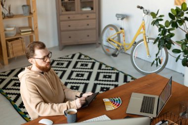 Kapüşonlu ressam ofiste oturup resim çizmekle meşgul.