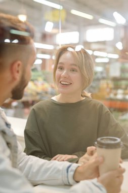 Birlikte kahve içerken sohbet eden pozitif, genç bir çift.