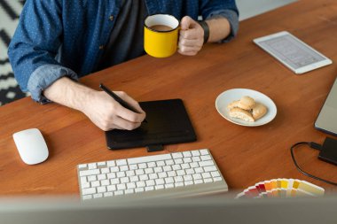 Kahve içen ve bilgisayar grafikleri üzerinde çalışırken tablet çizen tanımlanamayan tasarımcıların yakın çekimi