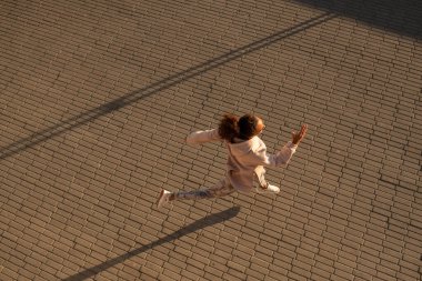 Tozlu bir sabahta beton kaldırımda koşan tozlu, kapüşonlu ve spor ayakkabılı genç sporcunun en iyi görüntüsü.