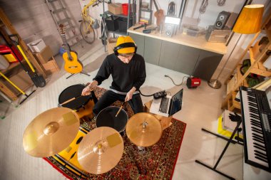 Kulaklıklı genç davulcu zil ve davulların üzerinde baget tutarken onları tek tek dövecek.