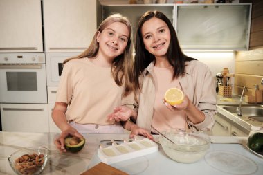 Taze limonlu genç bir kadın ve avokadolu kızı ev yapımı dondurmayı nasıl hazırlayacağını anlatırken sana bakıyor.