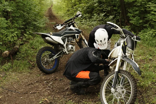 Kierowcy Skupieni Motocyklach Kaskach Sprawdzający Silnik Motocyklowy Razem Lesie — Zdjęcie stockowe