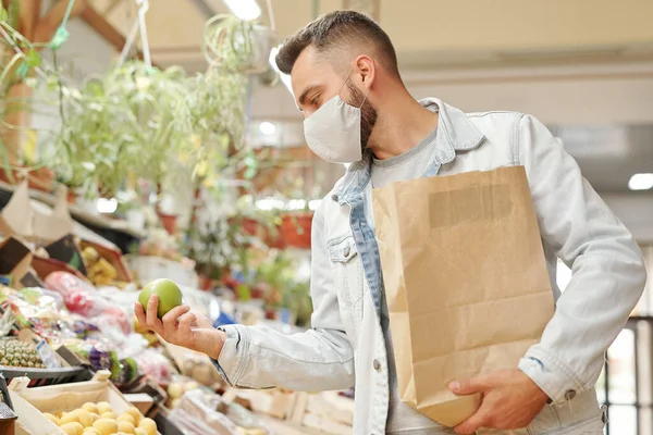 Hombre Joven Con Máscara Facial Sosteniendo Bolsa Papel Eligiendo Frutas —  Fotos de Stock