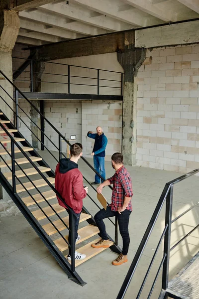 Twee Jonge Bouwers Werkkleding Staan Trappen Een Onafgewerkt Gebouw Luisteren — Stockfoto