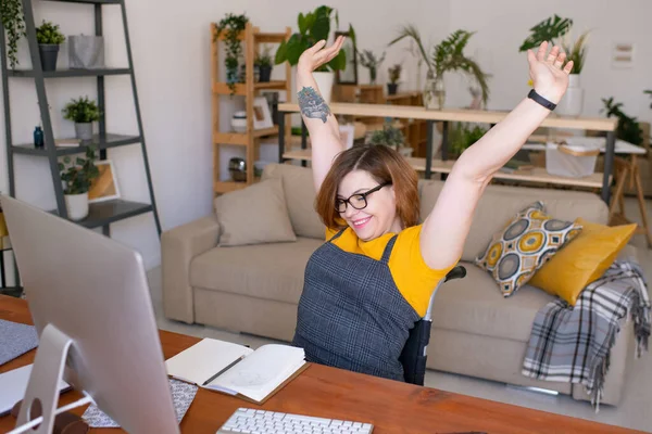 Evdeki çevrimiçi dersten sonra tekerlekli sandalyede otururken kollarını geren genç ve sakat kız öğrenci.