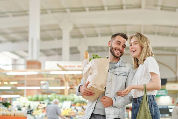 快乐的年轻夫妇站在农贸市场边聊天边购物 — 图库照片