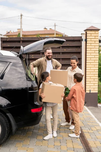 孩子们在开车时拿着东西 同时帮助父母在搬进新房子时卸下汽车 — 图库照片