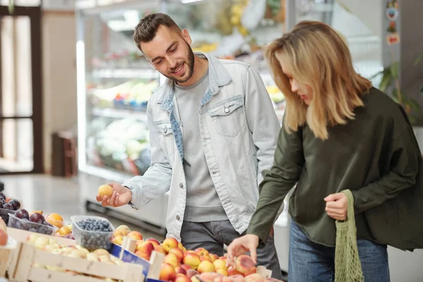 身着休闲装的年轻夫妇站在食品柜台前 在农贸市场上寻找成熟的水果 — 图库照片