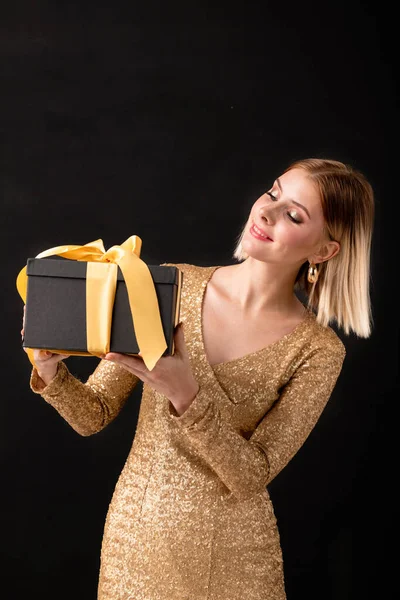 Jonge Elegante Vrouw Gouden Jurk Zoek Naar Zwart Giftbox Gebonden — Stockfoto