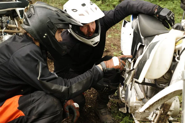 Skoncentrowani Motocykliści Kaskach Badający Patelnię Brzucha Motocykla Podczas Omawiania Przyczyny — Zdjęcie stockowe