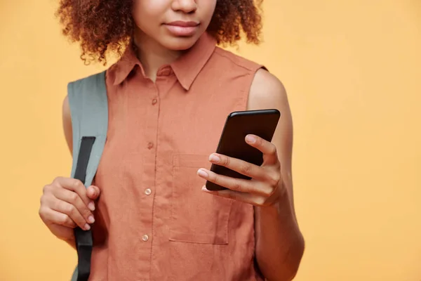 在黄色背景下 用智能手机紧紧抓住包扎和滚动社交媒体的黑人女生的特写 — 图库照片