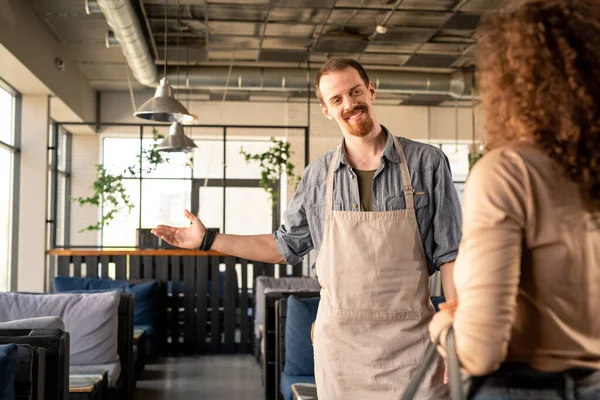 Stilig Ung Servitör Förkläde Gester Till Gratis Bord Samtidigt Välkomnande — Stockfoto