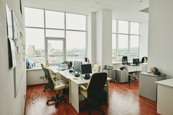 Interior of contemporary large office in modern center with desks, computer monitors, white leather armchairs and other stuff