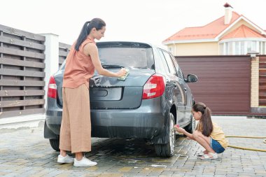 Şık bir anne ve kızı sabun ve sünger kullanarak birlikte vakit geçiriyorlar.