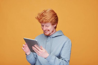 Maskeli, yorgun, genç, kızıl saçlı bir adam. Alnına dokunurken kötü hissediyor. Sıcaklığı ve koronavirüs konseptini kontrol ediyor.