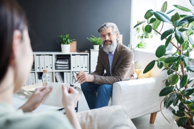 Ofisinde tanınmaz haldeki üzgün bir kadınla çalışan modern profesyonel psikolog.