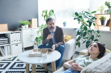 Ofisinde üzgün genç bir kadınla terapi seansında çalışan profesyonel bir psikolog.