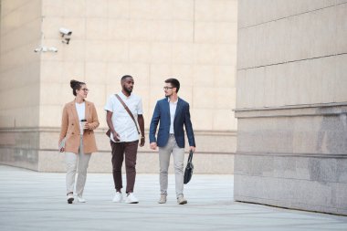 İş bölgesinde yürüyen ve proje promosyonundan bahseden kendinden emin genç iş uzmanları