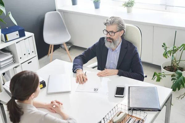 Modern şirket ofisinde iş görüşmesi yapan tanınmayan genç bir kadının yatay yüksek açılı görüntüsü.