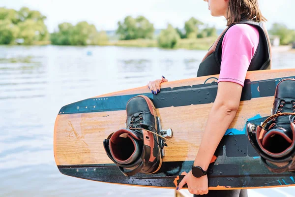 カメラの前で水辺に立っている間 スポーツウェア保持サーフボードでアクティブな若い女性サーファーとスポーツトレーニングを持っているだろう — ストック写真