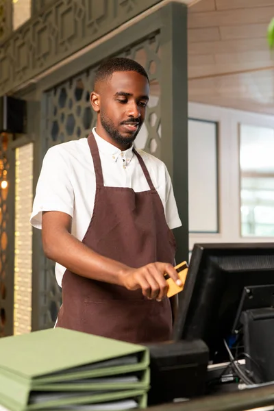 Jeune Serveur Caissier Tablier Marron Debout Devant Ordinateur Prenant Paiement — Photo