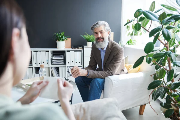 Ofisinde tanınmaz haldeki üzgün bir kadınla çalışan modern profesyonel psikolog.