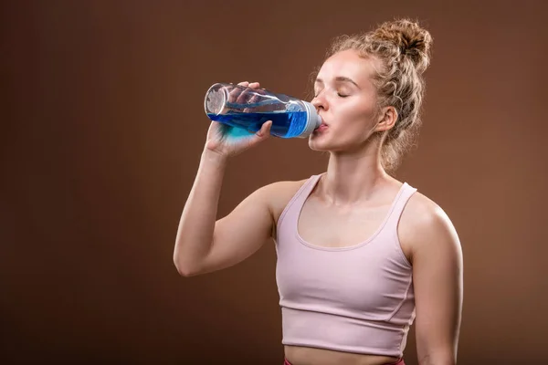 スポーツトレーニング後の休息とリフレッシュのための短い休憩をしながら 若いフィットのどが渇いたスポーツ女性は ペットボトルから水を飲む — ストック写真