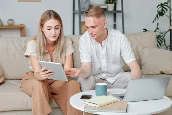 Kocasına danışmanlık yaparken internetten satın almak istediği şeyleri gösteren tabletli genç bir kadın.