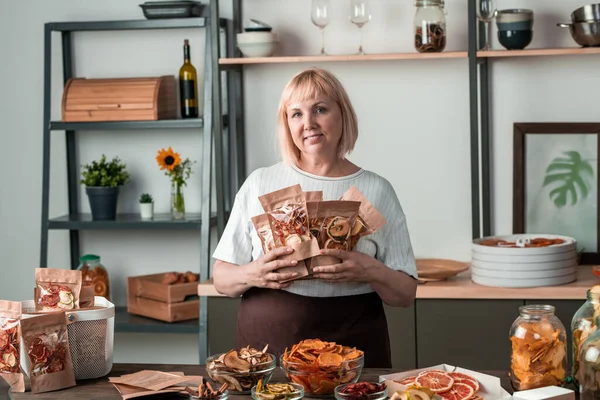 Çağdaş ev hanımının elinde, içinde ev yapımı kurutulmuş meyve bulunan birkaç paket kâğıt.