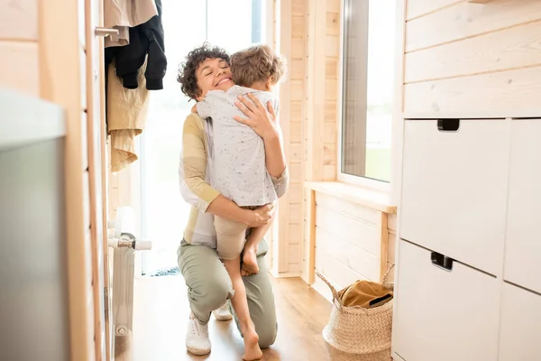 Jovem Mãe Alegre Joelho Chão Corredor Enquanto Abraça Seu Filhinho — Fotografia de Stock