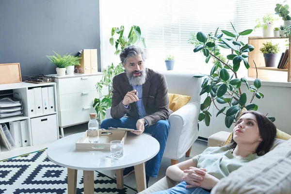 Ofisinde üzgün genç bir kadınla terapi seansında çalışan profesyonel bir psikolog.