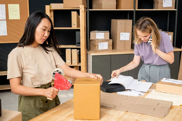 Ung Asiatisk Kvinna Tätning Packad Ordning Kartong Medan Hennes Kollega — Stockfoto