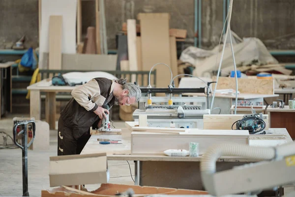 Kıdemli usta ya da ustabaşı yeni endüstriyel işlem makinesini işaret ediyor ve stajyeriyle toplantıda çalışma prensiplerini tartışıyor.