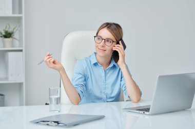 Genç, başarılı ve kendine güvenen bir şirket başkanı. Kulağında telefonla ofiste oturuyor ve müşterilerden birini dinliyor.